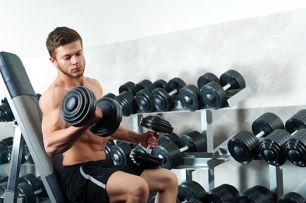 Hübscher junger Athlet, der im Fitnessstudio trainiert