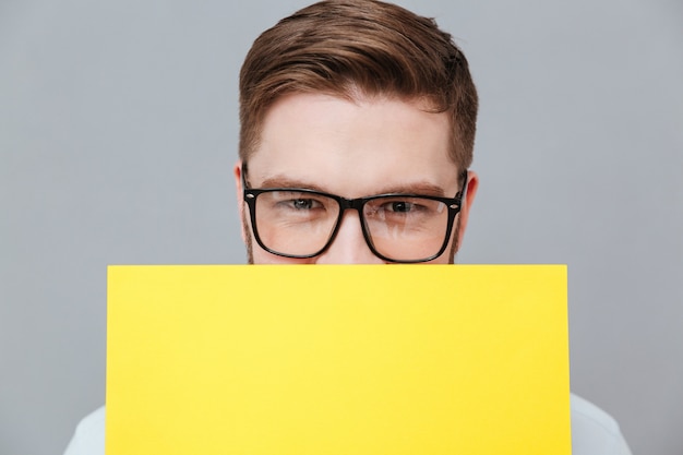 Kostenloses Foto hübscher junger bärtiger geschäftsmann, der leeres papier hält