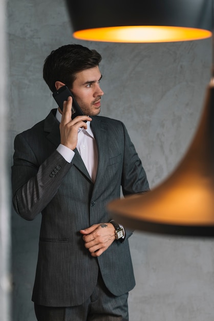 Hübscher junger Geschäftsmann, der auf Mobiltelefon spricht