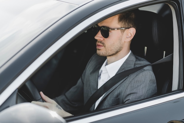 Hübscher junger Geschäftsmann, der Auto fährt