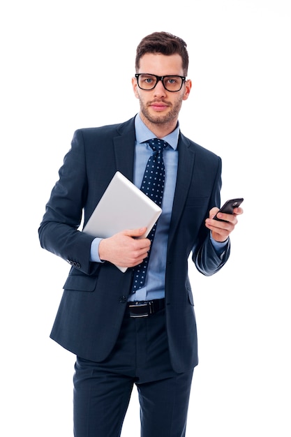 Hübscher junger Geschäftsmann mit einem digitalen Tablett und einem Mobiltelefon