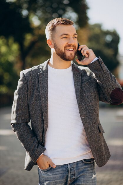 Hübscher junger Geschäftsmann mit Telefon außerhalb der Straße