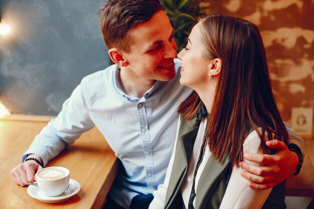 Kostenloses Foto hübscher junger kerl in einem blauen hemd, das in einem café zusammen mit ihrem netten mädchen i sitzt