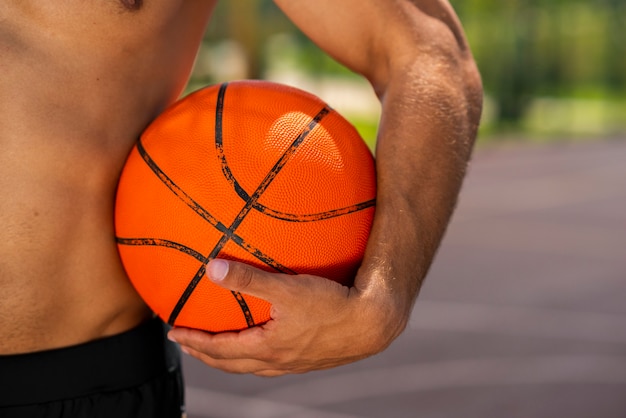 Hübscher junger mann, der einen basketball hält