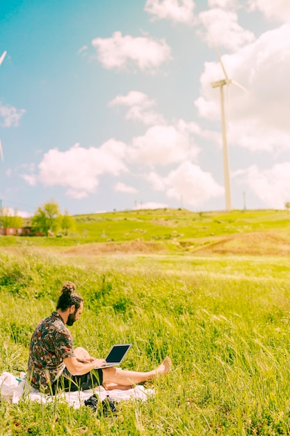 Hübscher junger Mann, der Laptop in der Landschaft hält