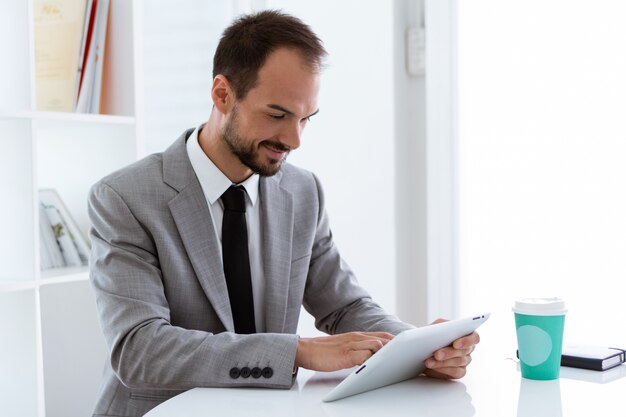 Hübscher junger Mann, der mit digitaler Tablette im Büro arbeitet.