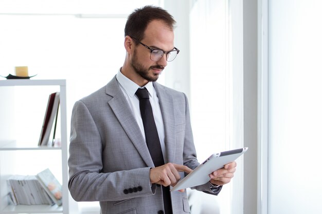 Hübscher junger Mann, der mit digitaler Tablette im Büro arbeitet.