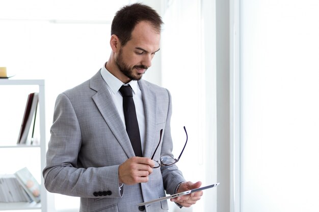 Hübscher junger Mann, der mit digitaler Tablette im Büro arbeitet.