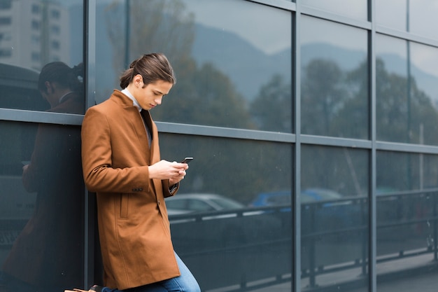 Hübscher junger Mann, der sein Telefon überprüft