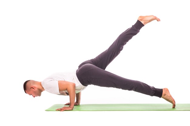 Hübscher junger Mann, der Yoga-Pose lokalisiert auf einem weißen Hintergrund tut