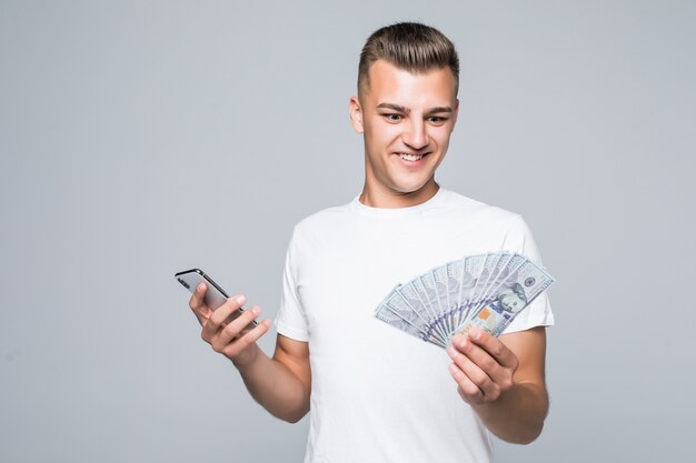 Hübscher junger Mann im weißen T-Shirt hält viele Dollarnoten in seinen Händen, die auf Weiß isoliert werden