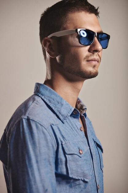 Hübscher junger Mann mit modischer Sonnenbrille im Studio