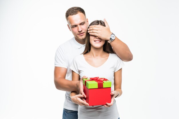 Hübscher junger Paarmann geben seiner Dame rote Geschenkboxüberraschung lokalisiert auf Weiß