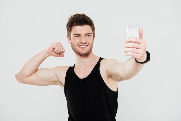 Hübscher junger Sportler mit Telefon machen Selfie