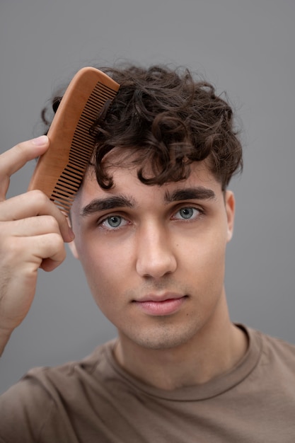 Kostenloses Foto hübscher kerl, der sein lockiges haar kämmt