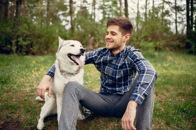 Hübscher Kerl in einem Sommerpark mit einem Hund