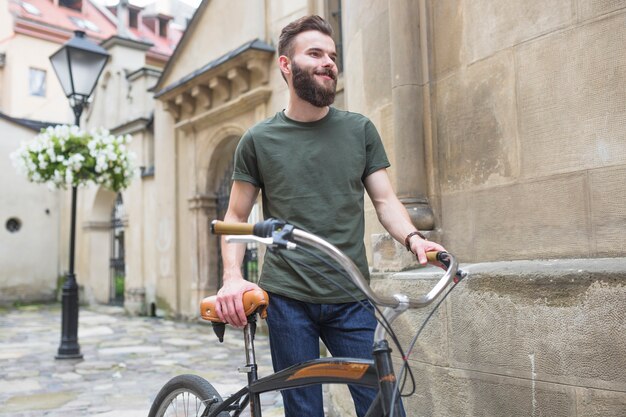 Hübscher Kerl mit Fahrrad in der Stadt