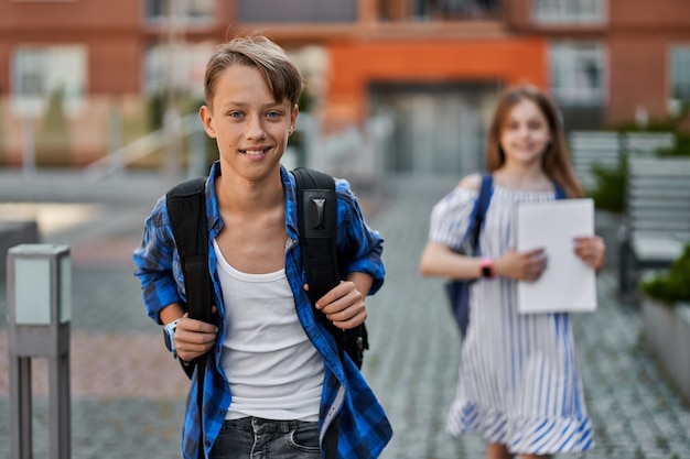 Hübscher kleiner Junge und hübsches Mädchen, das mit Rucksack und Büchern zur Schule geht.