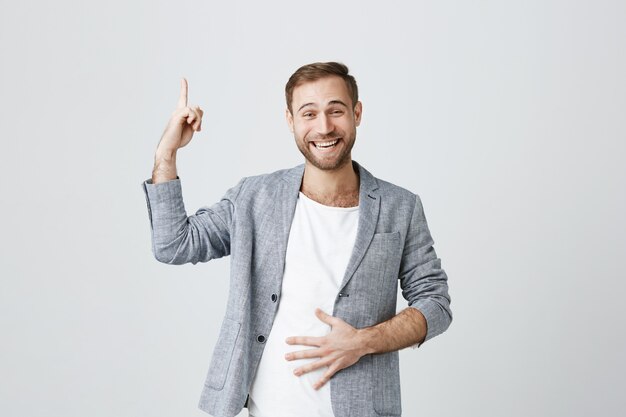 Hübscher lachender Mann, der Finger nach oben zeigt