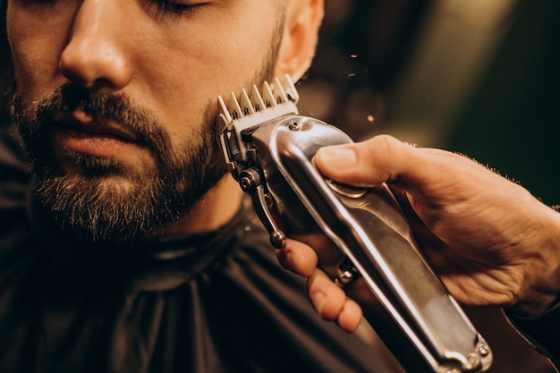 Hübscher Mann am Friseursalon, der Bart rasiert