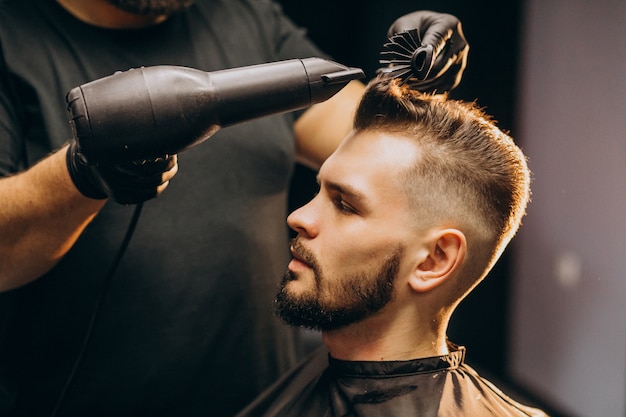 Hübscher Mann an einem Friseurladen, der Haare stylt