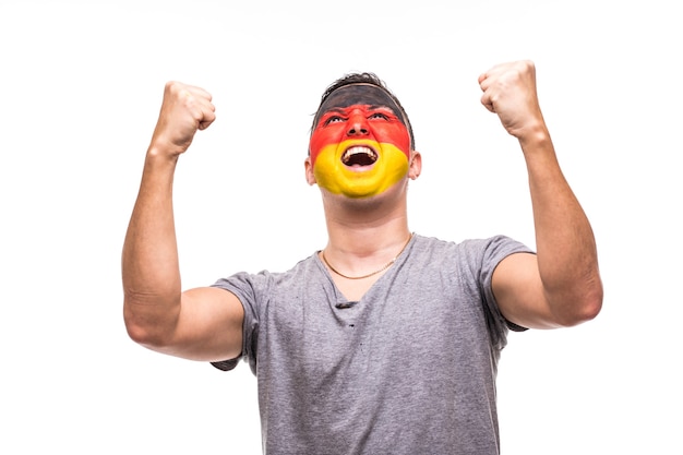 Hübscher Mann Anhänger Fan der deutschen Nationalmannschaft mit gemaltem Flaggengesicht erhalten glücklichen Sieg, der in eine Kamera schreit. Fans Emotionen.