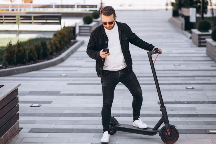 Kostenlose Foto hübscher mann auf roller, der online am telefon einkauft