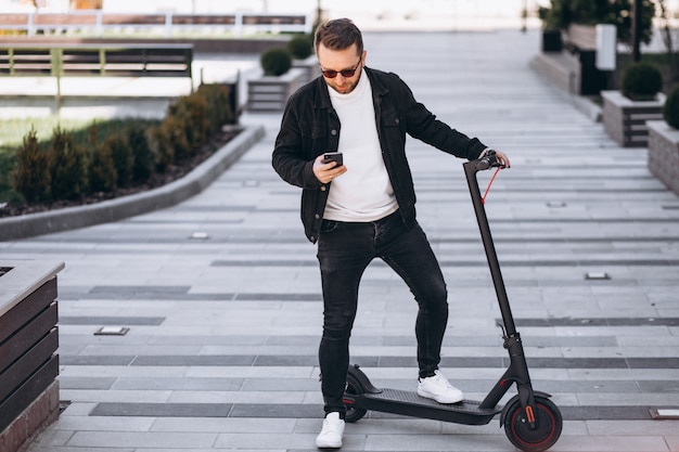 Hübscher Mann auf Roller, der online am Telefon einkauft