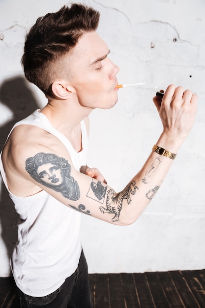 Kostenloses Foto hübscher mann, der auf boden mit zigarettenaufstellung steht