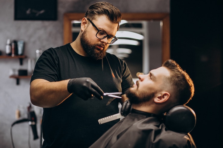 Kostenlose Foto hübscher mann, der bart an einem friseursalon schneidet