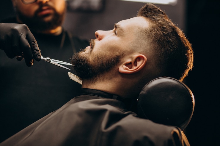 Kostenlose Foto hübscher mann, der bart an einem friseursalon schneidet