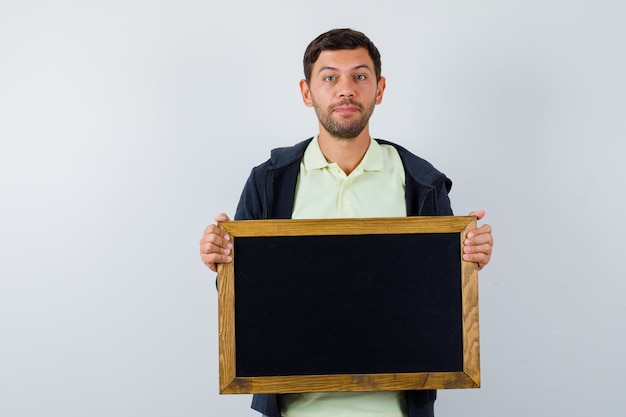 Hübscher Mann, der eine Tafel in einem lässigen Outfit hält