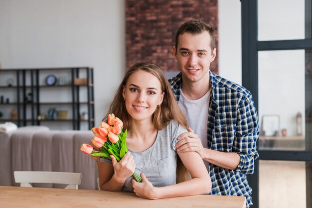 Hübscher Mann, der Frau mit schönen Blumen umarmt