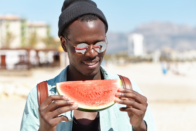 Hübscher Mann, der frische saftige Wassermelone genießt