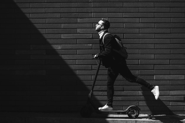 Hübscher Mann, der in der Stadt auf Roller reitet