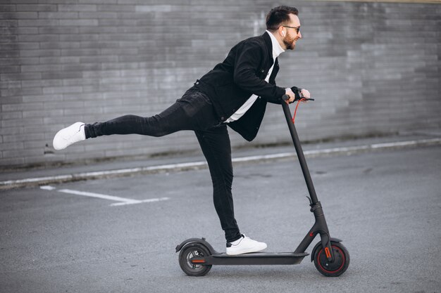 Hübscher Mann, der in der Stadt auf Roller reitet