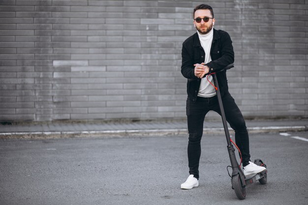 Hübscher Mann, der in der Stadt auf Roller reitet