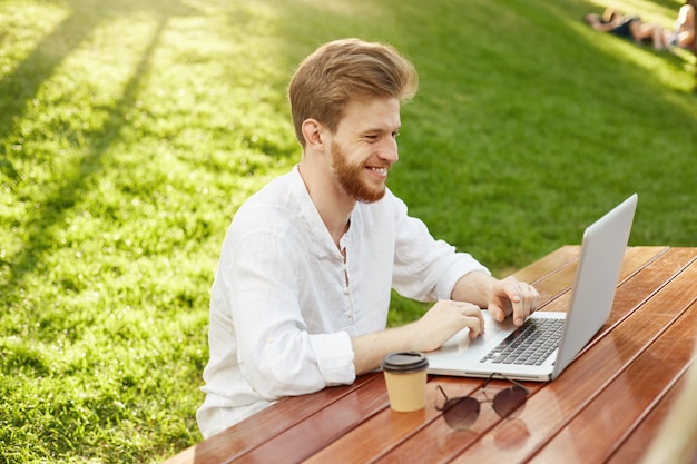 Hübscher Mann des reifen Ingwers mit Laptop-Computer im Park