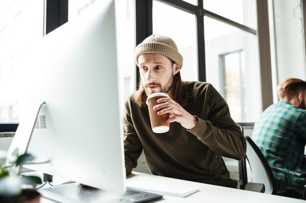 Hübscher Mann im Büro unter Verwendung des Computers