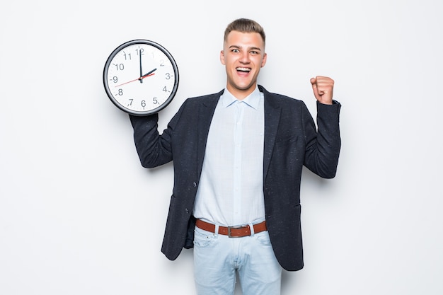 Hübscher Mann in der Suite halten große Uhr in einer Hand lokalisiert auf Weiß