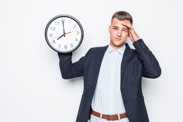 Hübscher Mann in der Suite halten große Uhr in einer Hand lokalisiert auf weißem, spätem Konzept