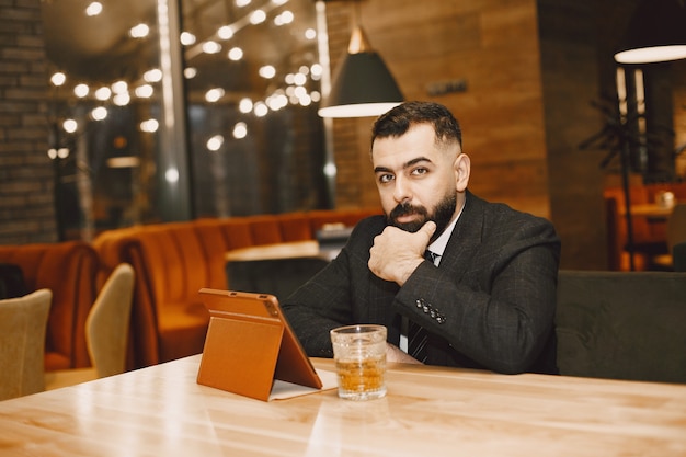 Hübscher Mann in einem schwarzen Anzug, der in einem Café arbeitet