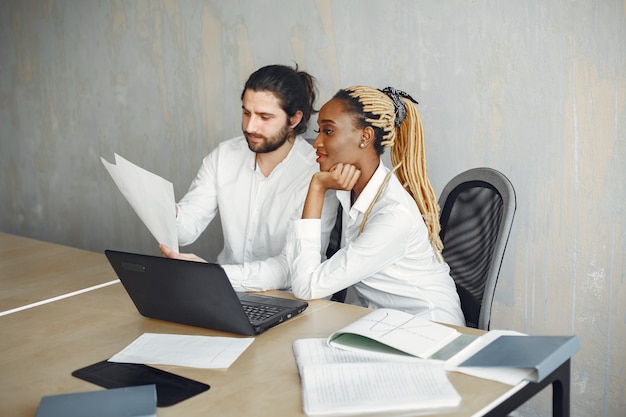 Hübscher Mann in einem weißen Hemd. Afrikanerin mit Partnerin. Kerl mit einem Laptop.