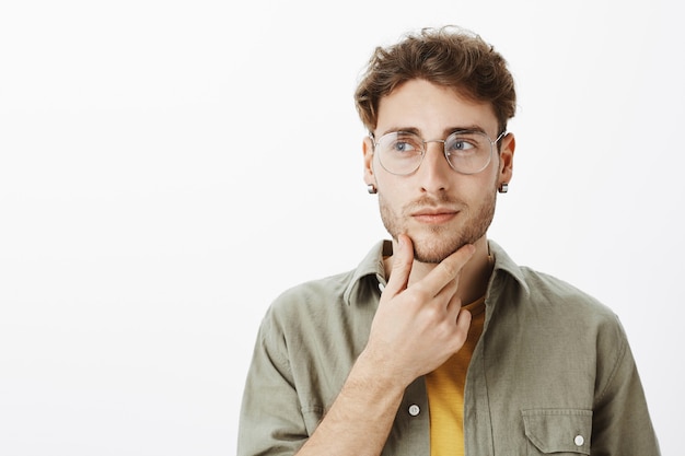 Kostenloses Foto hübscher mann mit brille, die im studio aufwirft