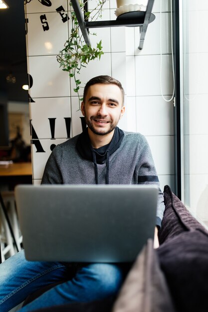 Hübscher Mann mit Laptop in einem Café