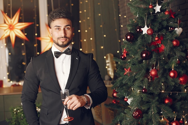 Hübscher Mann nahe Christmassbaum. Gentelman in einem schwarzen Anzug.