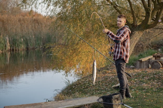 Hübscher Mann nahe Fluss an einem Fischermorgen