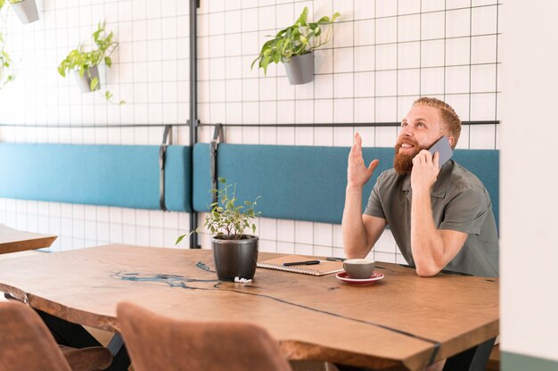 Kostenloses Foto hübscher moderner mann, der am telefon mit kopienraum spricht