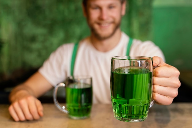 Kostenloses Foto hübscher smiley-mann, der st feiert. patrick's day mit getränken