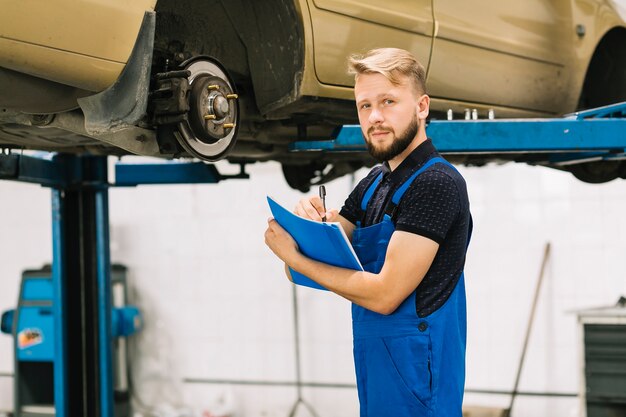 Hübscher Techniker, der an der Autowerkstatt arbeitet